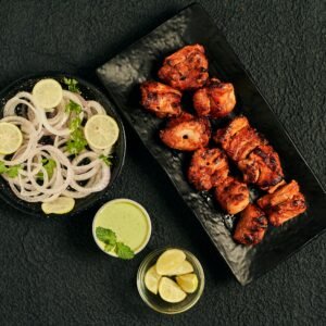Flat lay of juicy tandoori chicken pieces with onion salad and green chutney, perfect for Indian cuisine lovers.