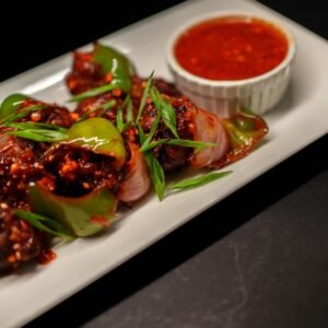 Close-up of spicy Indo-Chinese chilli chicken with sauce, garnished with spring onions.